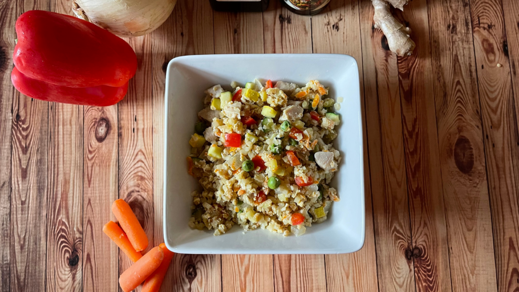 a white bowl filled with chicken cauliflower fried rice